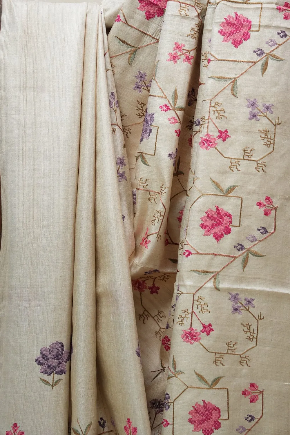 Handwoven 100% Pure Tussar Munga Silk Saree – Natural Cream By Bhavya loom_result Bhavyaloom natural cream 100 percent pure tussar muga silk saree with pink and purple floral hand embroidery draped on wooden stand